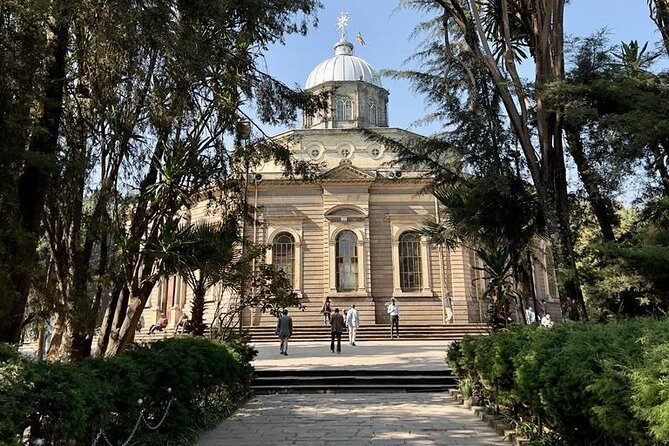 Holy Trinity Cathedral in Addis Ababa seen down a tree-lined avenue from its gate