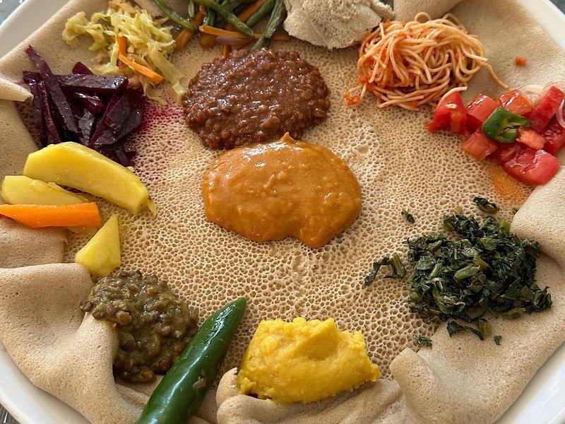 A shared platter of injera topped with Ethiopian stews, lentils and greens